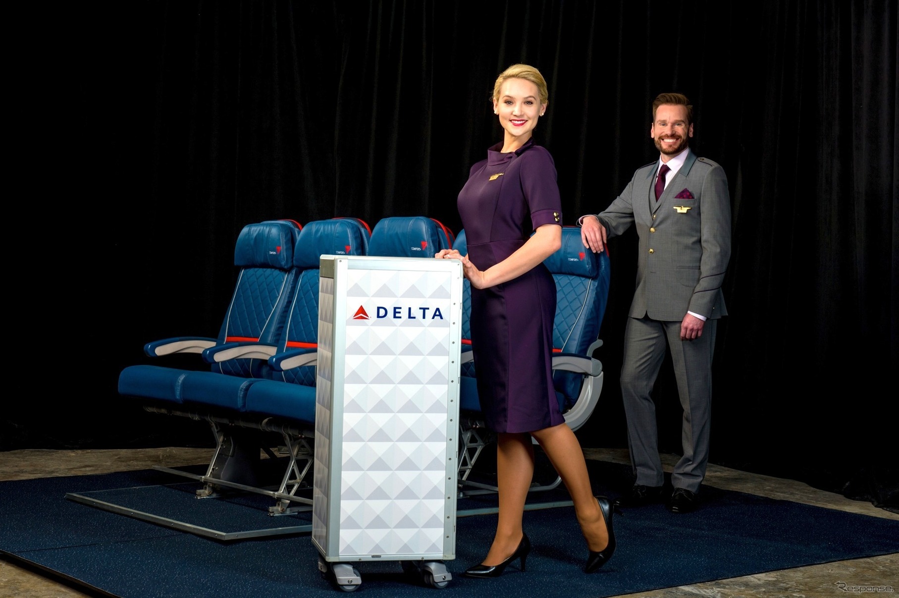 女性客室乗務員用パスポート・プラム色のVネックドレスと、男性客室乗務員用グランドスピード・グラファイト（濃いグレー色）のスリーピース・スーツ