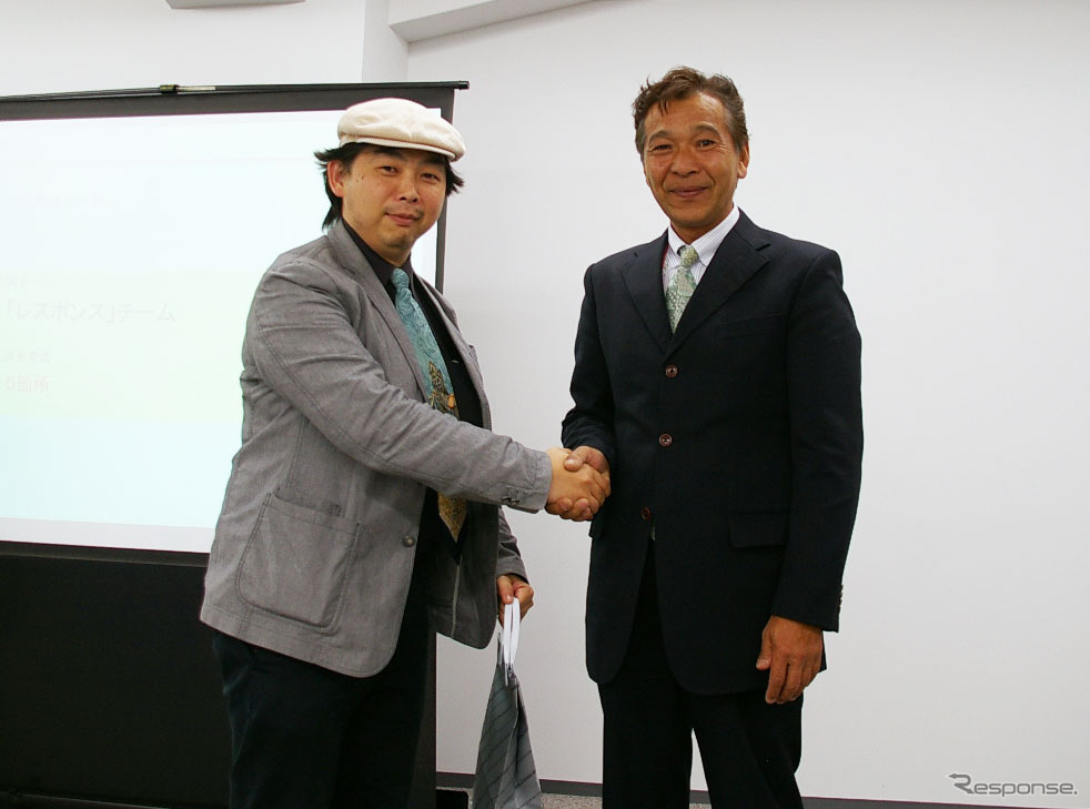 「たくさん充電したで賞」を頂戴し、大会委員長の増岡弘氏（右）と握手する筆者