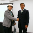 「たくさん充電したで賞」を頂戴し、大会委員長の増岡弘氏（右）と握手する筆者
