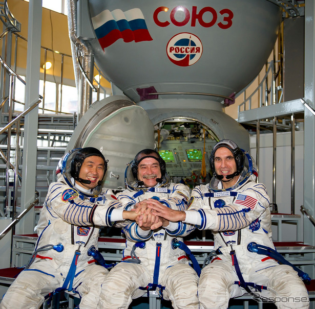 最終試験を終え、ソユーズ宇宙船シミュレータの前で手を握る若田光一、ミハイル・チューリン、リチャード・マストラキオ宇宙飛行士（左から）（出典：JAXA／GCTC）