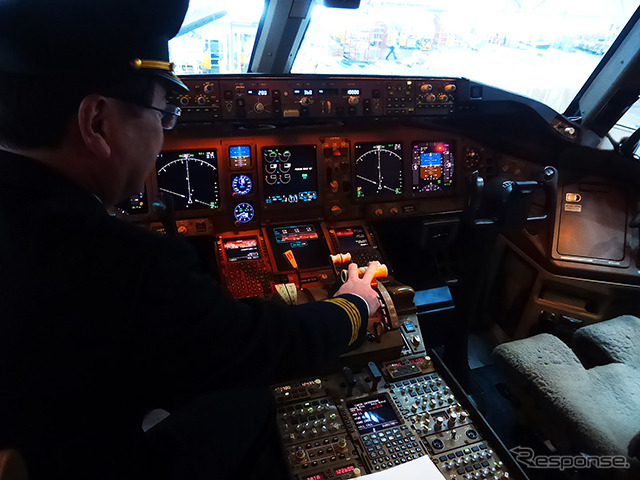 B777（JA8979）のコックピット。船越機長がスラスト・レバーに手をおく（羽田空港内JALメインテナンスセンター1（M1ハンガー））