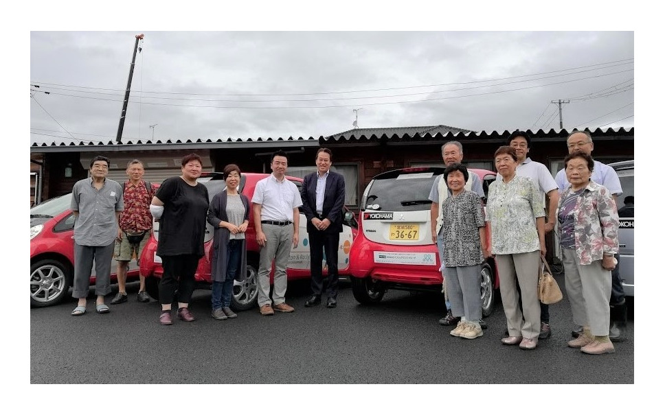 コミュニティ・カーシェアリングへのタイヤ寄贈セレモニーに参加した日本カーシェアリング協会の吉澤武彦代表理事(中央左)、横浜ゴムの森智朗CSR本部長代理(中央)とコミュニティ・カーシェアリングを利用する石巻市の人たち