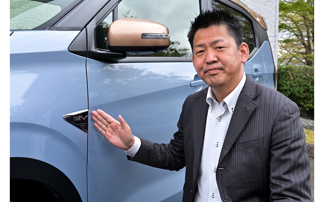 三菱自動車 商品企画本部チーフ・プロダクト・スペシャリストの藤井康輔氏とeKクロスEVの「EVエンブレム」