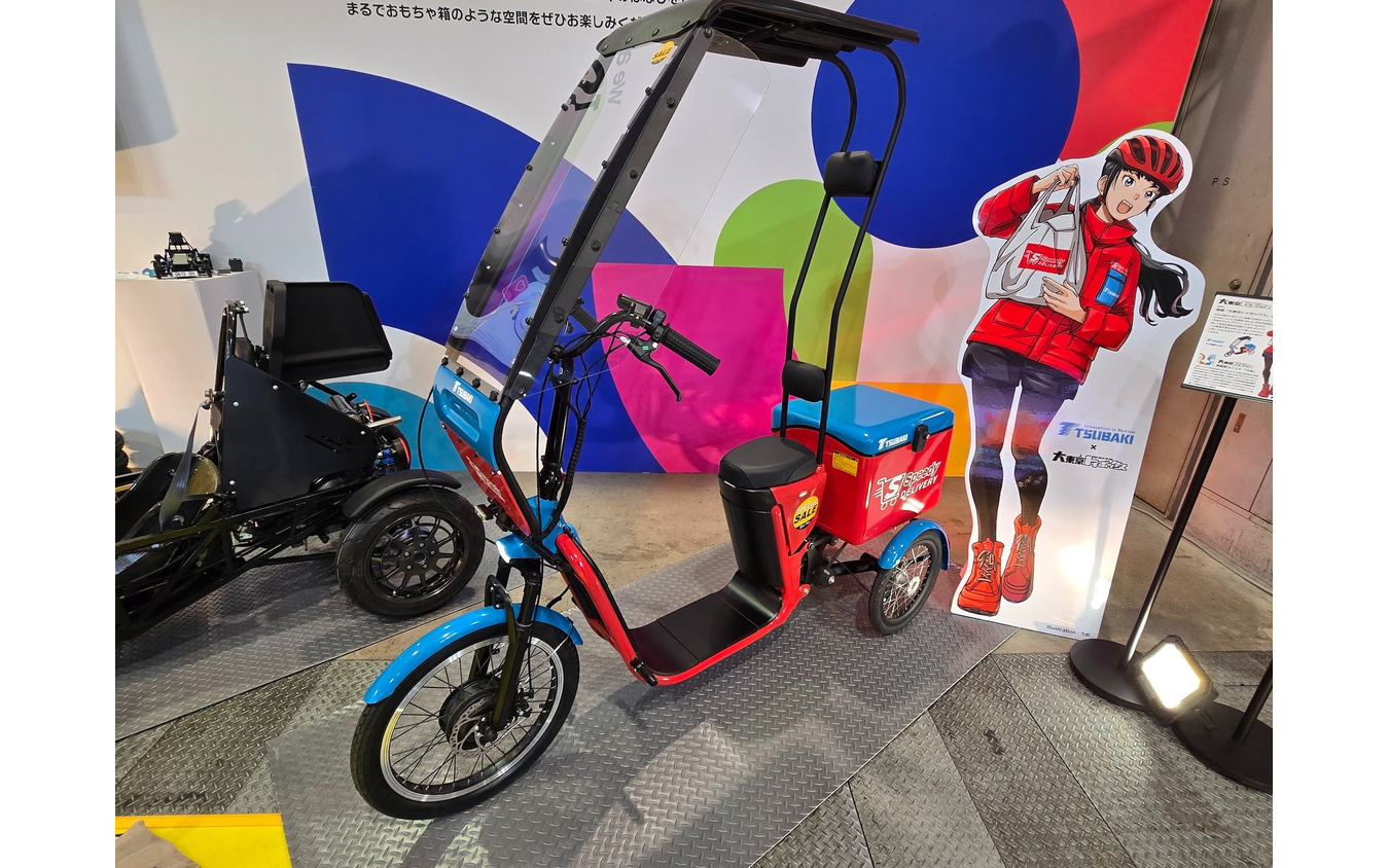 椿本チエインと共同開発した「Full電動Cargo（仮称）」。3輪構造で30kgまで積載可能な、デリバリー向け特定小型原動機付自転車。マンガ「大東京トイボックス」とのコラボイラストも展示中。