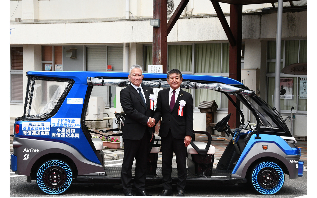 「奥永源寺けい流カー」の前で握手を交わす小椋正清市長（右）とブリヂストンの蓮沼 利幸氏（左）