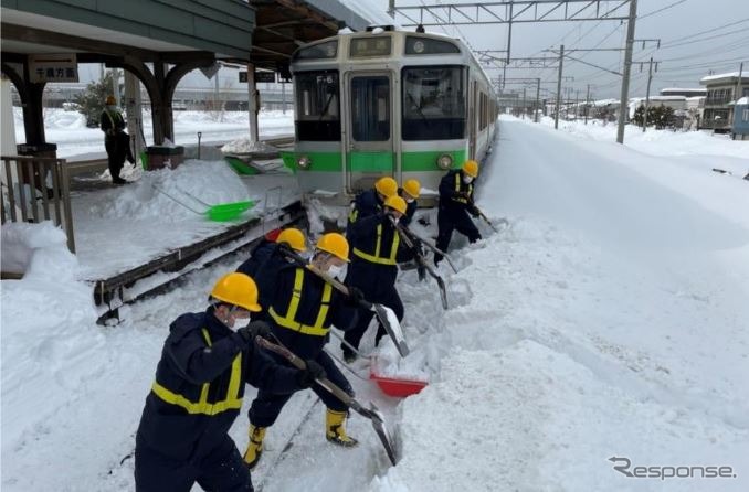 2月6日来の大雪で千歳線平和駅（札幌市厚別区）で立ち往生した721系普通列車の前で懸命に作業を行なう除雪作業員。