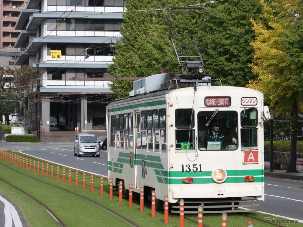 熊本市電の芝生軌道を走る1350形。タッチ決済またはQRコード決済の際は、乗務員への申し出が必要。