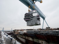 巨大なクレーンによって原子力空母ジェラルド・R.フォードの甲板に下ろされる艦橋 画像