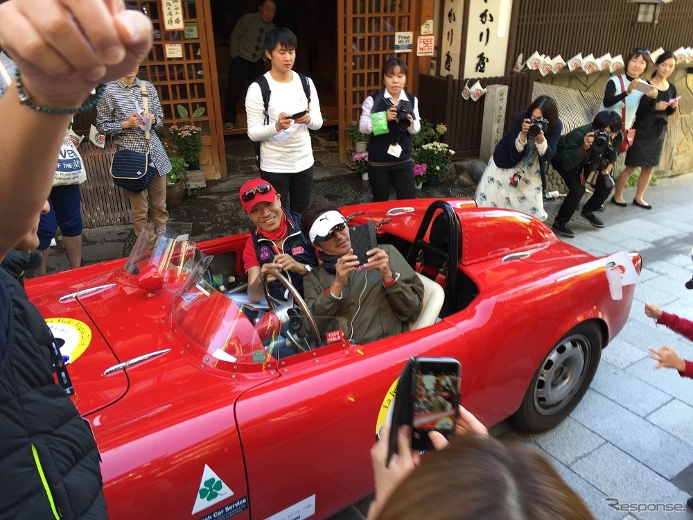 タレントでレーシングチームを率いる近藤真彦さんは、モータースポーツシーンに欠かせない存在だ。チェックポイントに到着すると背後の旅館金具屋さんの勇壮な姿にたちまち目をつけ、寸暇を惜しむように写真を撮っていた。