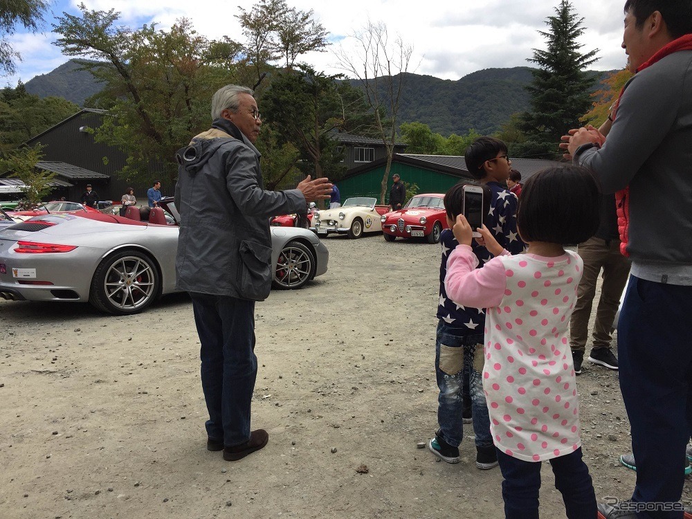 ずっとスマホを話し合ない少女。ずっとあたりにおいてあるあるクルマをくまなくアルバムに収めていた。