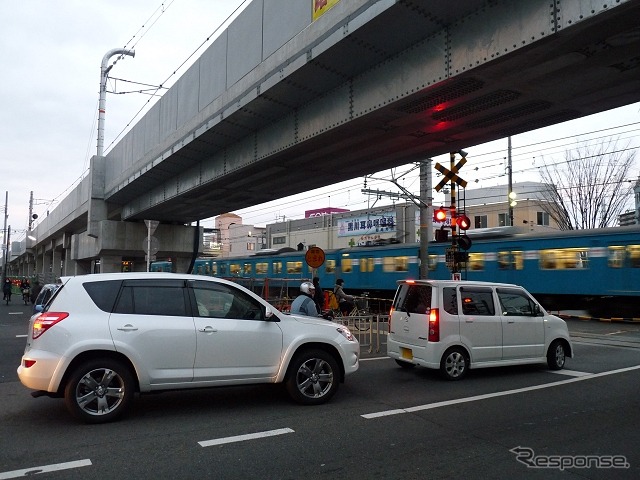 東岸和田駅付近の踏切（2015年1月）。上方に完成した下り線の高架橋が見える。奥に見える上り線も今年10月に高架化される。
