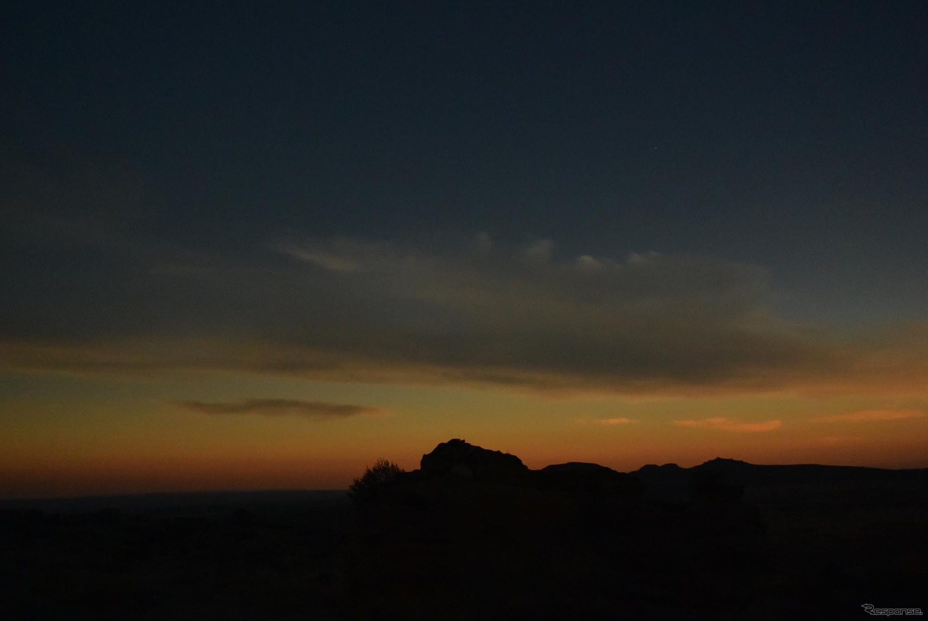 皆既日食中の地平線。上空は暗いが、50kmほど先は部分日食の日が照りつけており、その光で夕焼けのような色になる。