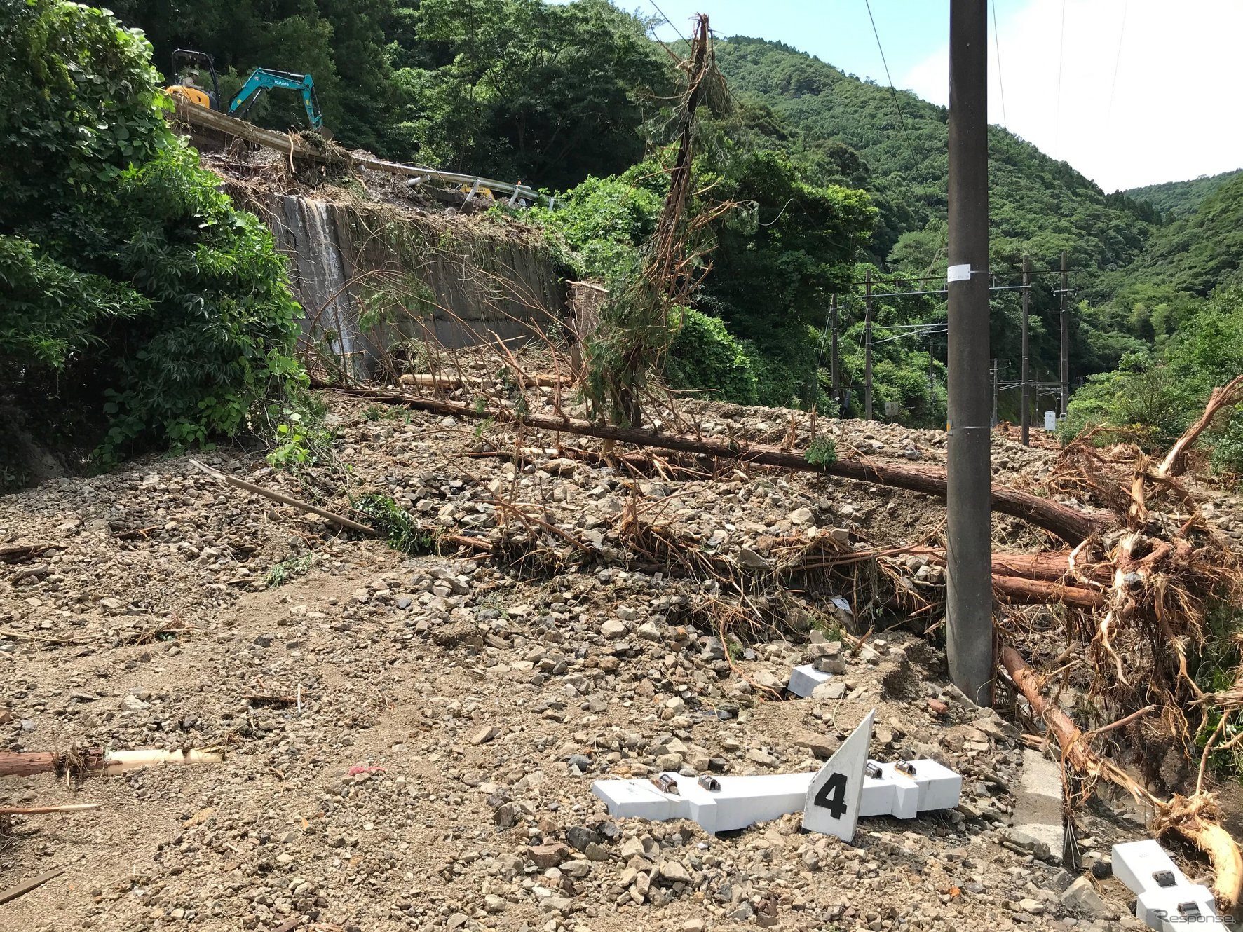 肥薩おれんじ鉄道で最も被害が大きい海浦～佐敷間の佐敷トンネル付近。左手の山から崩れた土砂と木々がその下の国道を巻き込んで大量に線路に流れ込み、佐敷トンネルの出入口が架線とともに完全に埋没した。