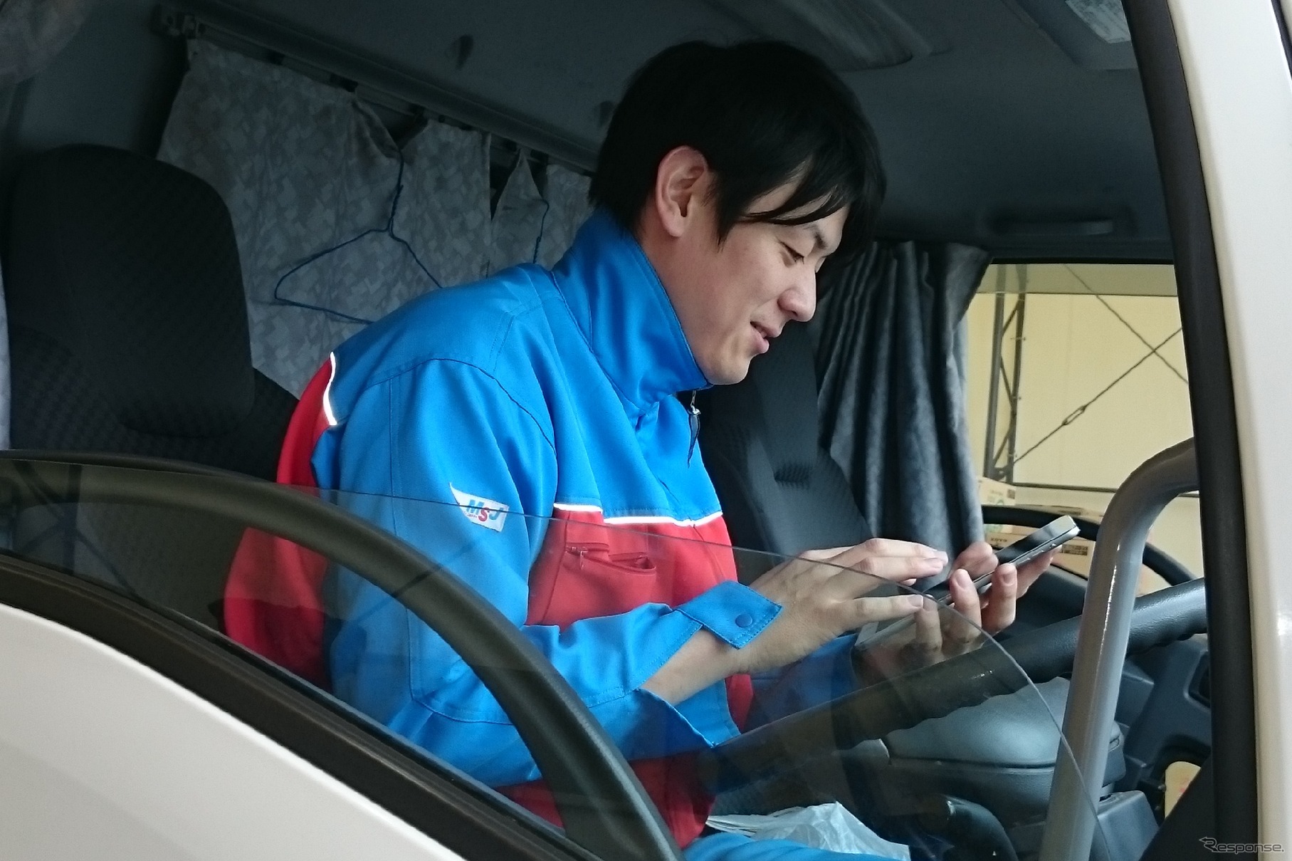 スマートフォンでATMTCアプリを操作するトラックドライバー