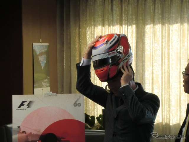 可夢偉にもらったヘルメットをかぶろうとする前原大臣