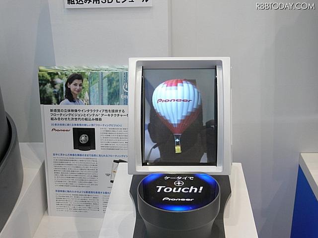 「フローティングビジョン」とFeliCaを連携させた提案。FeliCa対応の携帯電話を手前の台の上に置くと、「気球」の浮遊映像が携帯電話の中に飛び込むアニメーションが表示され、携帯電話にはURLなどの情報が取り込まれる