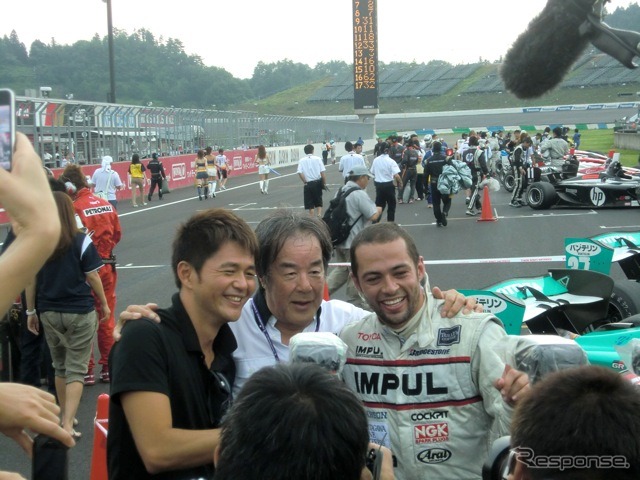 勝ったオリベイラ（右）と祝福する星野一義監督（中央）。星野監督に呼ばれて、かつての自軍エース・本山哲（左）も飛び入りで肩を組む
