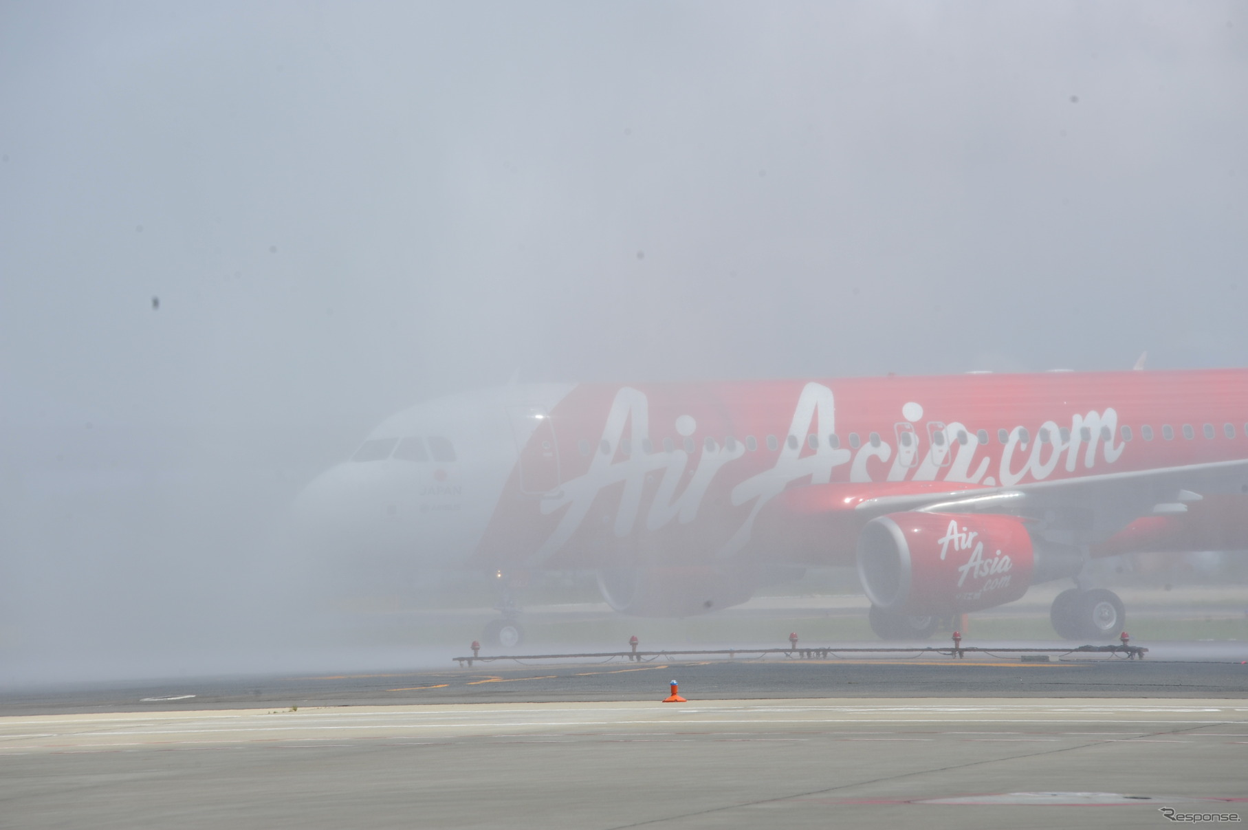 ゲートに向かうエアアジア・ジャパンの機体は、歓迎のウォーターサリュート（消防車の放水）の水煙に曇った（11日・成田国際空港）