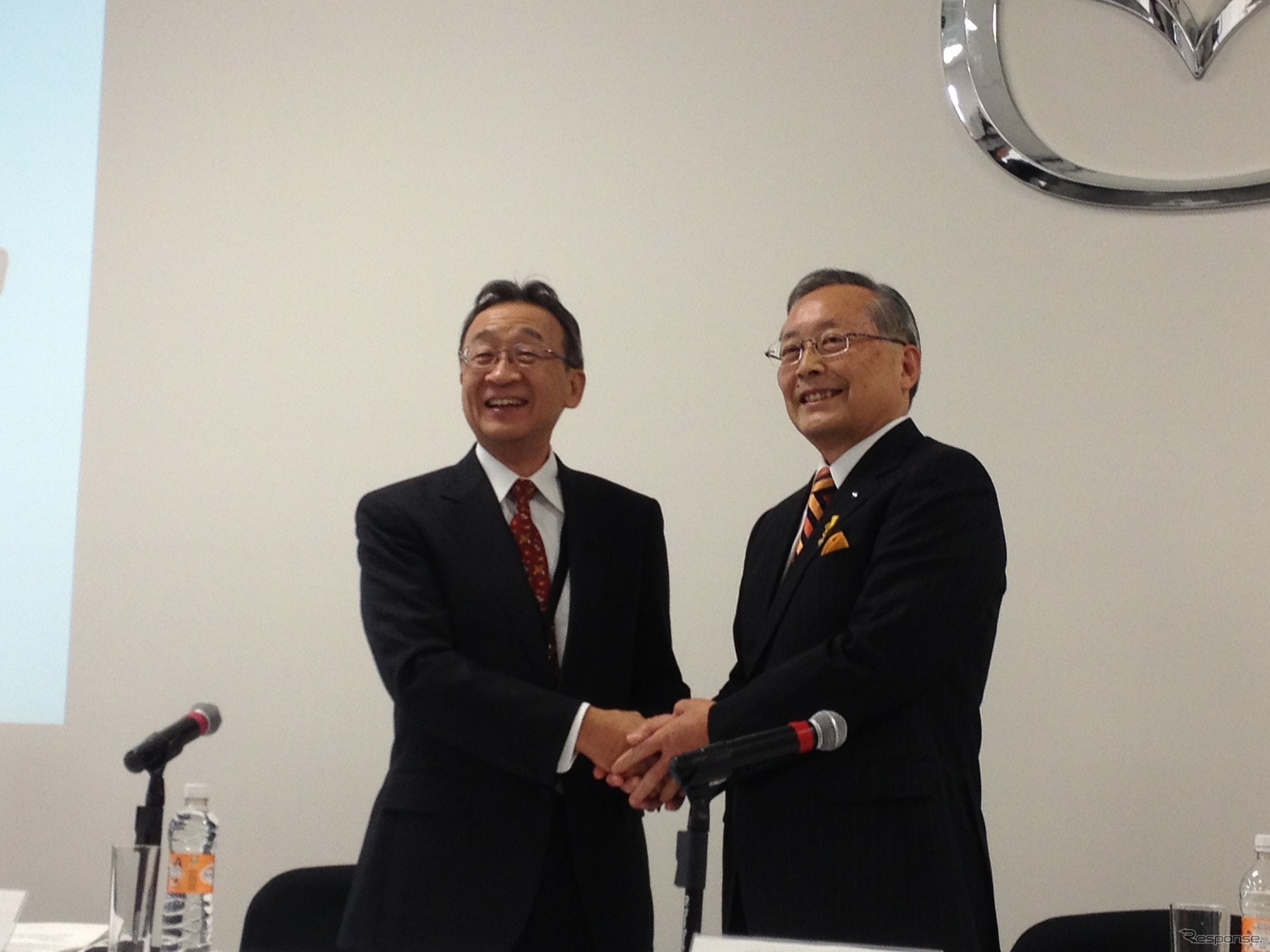 記者会見で握手する山内孝マツダ会長（右）と中村邦晴住友商事社長（左）