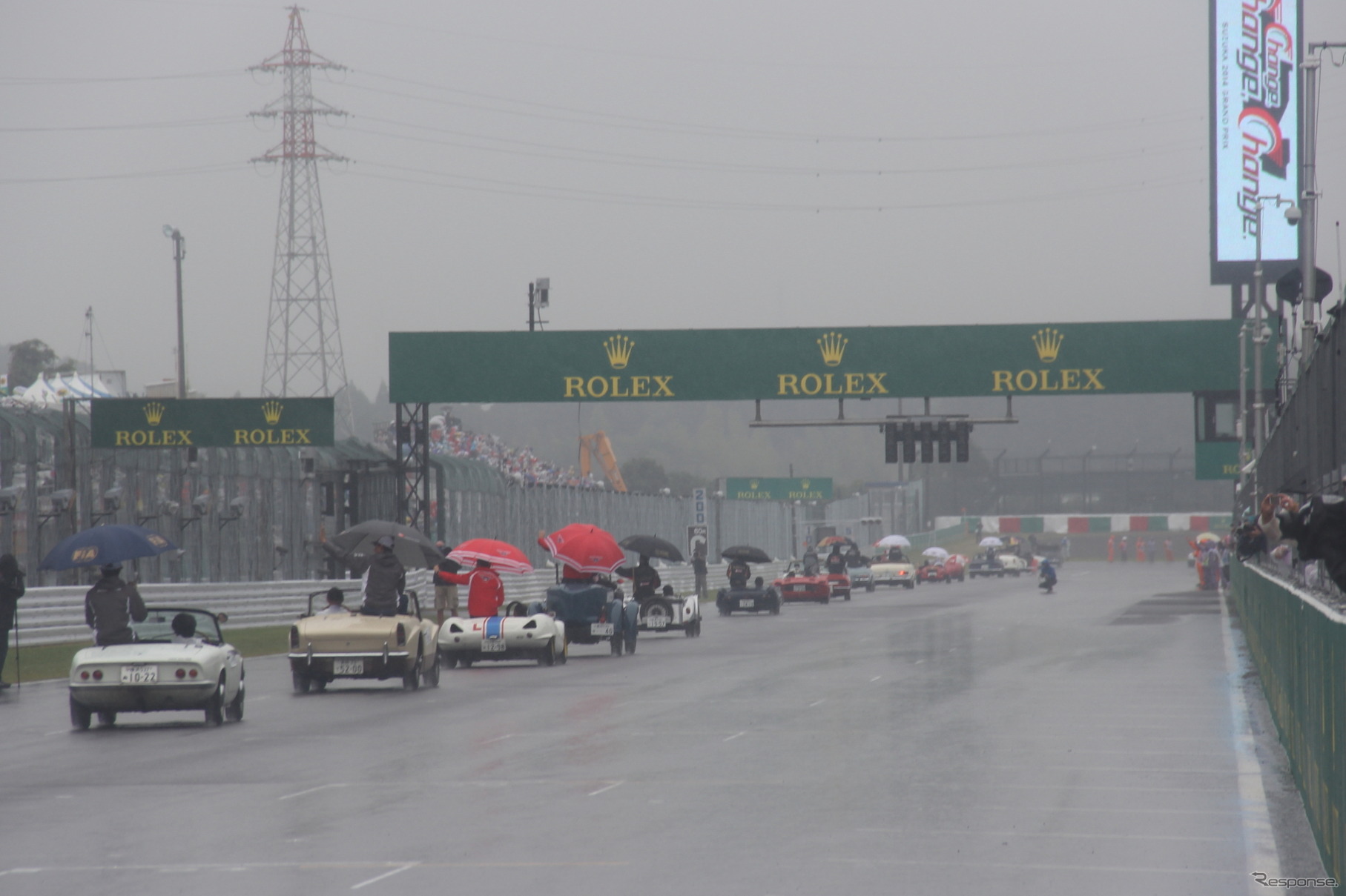 雨が中、クラシックカーに乗ってパレードに出発するドライバーたち