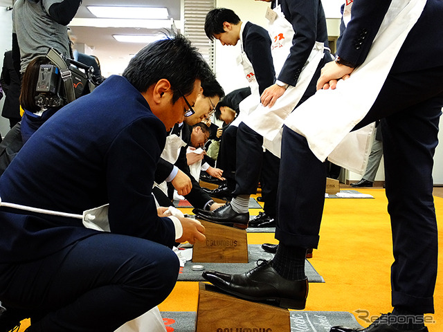 コロンブスの新人と社員が握手を交わし、先輩が手本を見せるかたちで新人の靴をみがき上げると、こんどは社員のアドバイスを聞きながら、新人たちが先輩の靴をみがいた（4月1日、コロンブス「靴みがき入社式」）