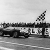 ランス12時間耐久でチェッカーを受けるジャガーDタイプ（1954年）。運転席はケン・ウォートン、組んだのはピーター・ホワイトヘッド。