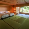 純和風の部屋の面影を残す居間の畳、そこに快適な睡眠の時を過ごせるようベッドを配置。ベッドサイドにはアンティーク風の照明。