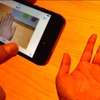 写真、電球色のライトのもとiPhone 5で撮影すると手がオレンジ色になってしまう。一方、iPhone 5sで撮影した画像を見ると自然な肌色となっている。