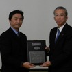 贈呈式の様子、本田技研工業 グローバル購買企画室室長 斎藤博氏（左）とブリヂストン常務執行役員 安全・防災・品質管掌 山口裕氏