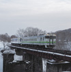 清水沢～鹿ノ谷間を行く下り列車。清水沢駅に近いこの志幌加別川付近は、手前に夕張支線がかつて複線であったことを物語る橋脚が残されている。2019年3月27日。