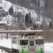 鹿ノ谷駅を出た新夕張行き列車。ヘッドマークは前後で異なるデザイン。車両も前からJR北海道色、「北海道の恵み」色、日高色と1両ずつ異なる塗色だった。2019年3月30日撮影。