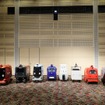 ロボットデリバリー協会各社の自動配送ロボット：向かって右から川崎重工業、ZMP、TIS、ティアフォー、日本郵便、パナソニック、本田技研工業、楽天グループ