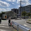 引込線跡。撮影者の左後方が所沢駅で、写真手前のガードレール左側が線路敷地。ガラス面の建物は廃線後にできたと思われ、線路は右にカーブしながら奥の工場に繋がっていた（9月18日）
