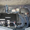 フロアボードを2枚重ねした3層構造のラゲッジの奥底にはパワーアンプやDSPなどが整然とレイアウトされている。