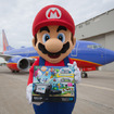 空港で任天堂のWii Uのゲーム機をプレゼントするマリオ