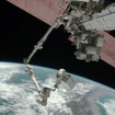 若田宇宙飛行士が操作するロボットアームの先端に乗ってポンプモジュールを運ぶホプキンス宇宙飛行士（出典：JAXA／NASA）