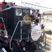 嵯峨野トロッコ列車の年間利用者数が3月19日、初めて100万人を突破した。写真は記念のヘッドマークを取り付ける乗客代表ら