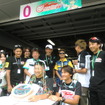 GT300の#0 SLSを駆る片岡龍也（前列左）が前戦で100戦出走に到達。ピットウォーク中に僚友の谷口信輝（前列右）、チームスタッフらがお祝いを実施。片山右京監督の姿も（後列右から2人目）。