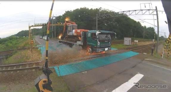 トロリ線に接触し、重機から火花を散らすダンプカー。